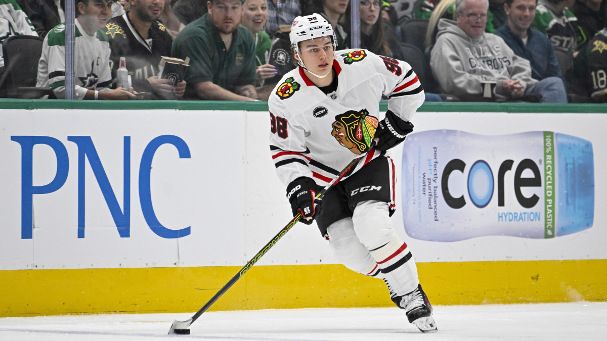 Connor Bedard handles the puck in a white Blackhawks jersey